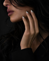 Close-up of a woman's face with hand near her ear against a dark background