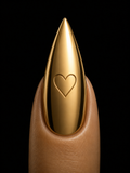Gold nail tip with a heart design on a black background